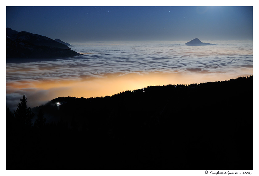 Paysage des Alpes la nuit - Mer de nuage claire par la lune et les lumires de Cluses et des Carroz, sur la valle le L'Arve. Le Mle (1860m) est presque englouti dans la masse nuageuse.